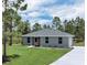 Charming single-story home featuring a well-manicured lawn, fresh landscaping, and a classic gray exterior at 3120 Oleander Dr, Indian Lake Estates, FL 33855