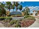 Community entrance sign surrounded by lush landscaping, mature palm trees, and vibrant flowering plants at 3710 Plymouth Dr, Winter Haven, FL 33884
