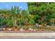 Lush landscaping with mature trees, colorful flowers, and decorative yard ornaments creates a welcoming garden area at 3710 Plymouth Dr, Winter Haven, FL 33884
