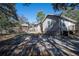 Exterior view of the house showcases its backyard featuring a deck, Tiki hut, and mature trees at 4010 Paw Paw Trl, Lake Wales, FL 33898