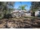 Exterior view from the backyard of the property highlighting the deck, Tiki hut, mature trees, and landscaping at 4010 Paw Paw Trl, Lake Wales, FL 33898