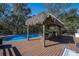Backyard oasis boasts a sparkling pool, a tiki hut, and a spacious deck, perfect for relaxation and entertaining at 4010 Paw Paw Trl, Lake Wales, FL 33898