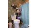 View of bathroom with toilet, shower curtain, metal storage rack, and leafy pattern wallpaper at 4063 Birkdale Dr, Lake Wales, FL 33859