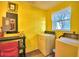 Functional laundry room with washer, dryer, and storage, featuring bright yellow walls at 4229 Nandina St, Lake Wales, FL 33898