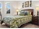 Bedroom with queen bed, leaf pattern bedding, nightstands with lamps, and window for natural light at 4313 Heath Land Ln, Lake Wales, FL 33859