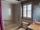 Bathroom with a tile shower and tub combo, complemented by floral wallpaper and shuttered window at 460 Pinehurst Ct, Winter Haven, FL 33884