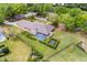 An aerial view displays the house, screened-in pool, manicured lawn, and lush landscaping at 5020 Broadmore Dr, Auburndale, FL 33823