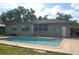 Rear view of a home with a sparkling swimming pool, patio area, and well-maintained landscaping at 614 Chatham Dr, Lakeland, FL 33803