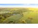 Expansive aerial view of sprawling green pasture land with scattered trees and location marker under a bright, clear sky at 6430 Russo Rd, Bartow, FL 33830