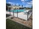 Community pool area surrounded by a security fence, pool furniture, and lush landscaping at 6603 Scenic Point Se Dr, Winter Haven, FL 33884