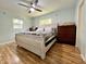 Bright bedroom with a ceiling fan, warm wood flooring, and a large, cozy bed at 799 W Lake Otis Dr, Winter Haven, FL 33880