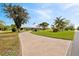 Long, patterned driveway leading to a charming home with an American flag and mature trees at 8947 Oakwood Dr, Lake Wales, FL 33898