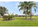 Beautifully landscaped front yard with lush green grass, palm trees, and manicured garden beds at 8947 Oakwood Dr, Lake Wales, FL 33898