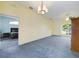 Bright living room with neutral walls, plush carpeting, and a glimpse into an adjacent bedroom through an arched doorway at 7726 Ashford Dr, Lakeland, FL 33810