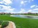 Scenic backyard view of a pond surrounded by lush green grass and landscaping, perfect for enjoying the outdoors at 1057 Sawgrass Dr, Winter Haven, FL 33884
