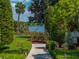 Lush backyard landscaping, manicured hedges, and mature trees offer privacy with a lake view at 125 E Graham Park Dr, Haines City, FL 33844
