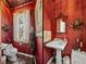 Half bath with red accent wall, pedestal sink and marble floors at 125 E Graham Park Dr, Haines City, FL 33844