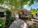 Charming walkway with lush gardens, bougainvillea, and mature trees provides a serene backyard setting at 125 E Graham Park Dr, Haines City, FL 33844