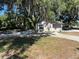 House with concrete driveway surrounded by mature trees providing ample shade at 180 Old Connersville Rd, Bartow, FL 33830