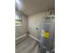 Bright laundry room features wood-look flooring, a black framed window, and water heater at 180 Old Connersville Rd, Bartow, FL 33830