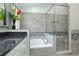 Well-lit bathroom featuring a granite countertop, soaking tub, glass shower with mosaic tile accents, and gray wood-look tile at 1942 Bermuda Pointe Dr, Haines City, FL 33844