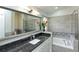 A modern bathroom featuring a granite countertop, gray tile, large mirror, soaking tub, and glass shower at 1942 Bermuda Pointe Dr, Haines City, FL 33844