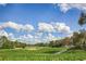 Scenic golf course view featuring lush green fairways, trees, and expansive sky with puffy clouds at 1942 Bermuda Pointe Dr, Haines City, FL 33844