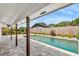 View of the in-ground pool from the covered patio with wood supports at 2096 Lake Ariana Blvd, Auburndale, FL 33823