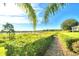 Picturesque brick path through manicured hedges leads to a tranquil lake, offering scenic views at 2654 Rutledge Ct, Winter Haven, FL 33884