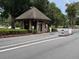 Community entrance featuring a gatehouse with security access, mature trees, and detailed landscaping at 409 Greenfield Rd, Winter Haven, FL 33884