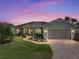 Charming single-story home with a well-maintained lawn, brick driveway, and inviting curb appeal at sunset at 4279 Ashton Club Dr, Lake Wales, FL 33859