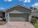 Attached two-car garage featuring brick paver driveway surrounded by colorful flowers and lush grass at 4279 Ashton Club Dr, Lake Wales, FL 33859