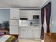 Efficiency kitchenette featuring white cabinets, compact appliances, sink, and an adjacent bed in a cozy setup at 43420 Highway 27 # 445, Davenport, FL 33837