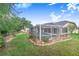 Screened pool area is set in a large, grassy backyard, next to a home with a red door at 508 Starr Ridge Dr, Lake Wales, FL 33898