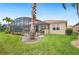 Backyard view featuring a large screened-in lanai and lush landscaping at 5200 Pebble Beach Blvd, Winter Haven, FL 33884