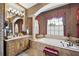 Elegant bathroom featuring a soaking tub, column, and decorative window with bright natural light at 5200 Pebble Beach Blvd, Winter Haven, FL 33884