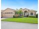 Inviting single-story home with lush landscaping, a brick walkway, and an arched entrance at 5200 Pebble Beach Blvd, Winter Haven, FL 33884