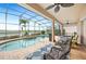 Covered patio with a lovely lounge area adjacent to a sparkling screened-in pool and scenic lake view at 5200 Pebble Beach Blvd, Winter Haven, FL 33884