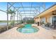Screened-in pool and spa area overlooking a serene lake view, perfect for relaxation and entertainment at 5200 Pebble Beach Blvd, Winter Haven, FL 33884