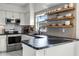 Bright kitchen features granite countertops, stainless steel appliances, and floating wood shelves at 530 Eastlake Dr, Haines City, FL 33844
