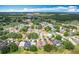 High angle aerial view of a beautiful neighborhood surrounded by mature trees and a nearby lake at 571 Saint Andrews Rd, Winter Haven, FL 33884