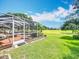 View of a screened-in patio extending to the lawn, creating an outdoor living space at 571 Saint Andrews Rd, Winter Haven, FL 33884