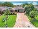 Charming home featuring a brick driveway, lush green lawn, and mature trees, creating a welcoming outdoor space at 571 Saint Andrews Rd, Winter Haven, FL 33884