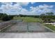 Aerial view of tennis courts and pool, with a golf course in the background under a bright blue sky at 571 Saint Andrews Rd, Winter Haven, FL 33884