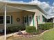Close-up of a home's front entrance with green shutters, a storm door and landscaped garden bed at 6107 Grand Oaks Se Dr, Winter Haven, FL 33884