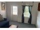Living room featuring a blue sofa, door to the exterior, and patterned curtains at 6107 Grand Oaks Se Dr, Winter Haven, FL 33884