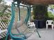 Cozy patio area with a green swing bench, white chairs, and lush greenery surrounding the space at 6107 Grand Oaks Se Dr, Winter Haven, FL 33884