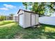 Exterior of a light-colored shed with a roll-up door in the backyard at 612 Ralph St, Auburndale, FL 33823