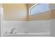 A bright white soaking tub is surrounded by white tiling and a sunny window at 6560 Horizon Point Dr, Lakeland, FL 33813