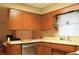 Functional kitchen showcasing wood cabinets, a dishwasher, and views into an adjacent room at 670 Avenue N Se, Winter Haven, FL 33880